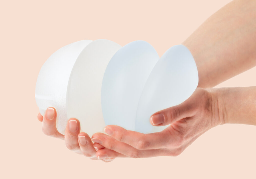 Hands holding breast implants of different sizes